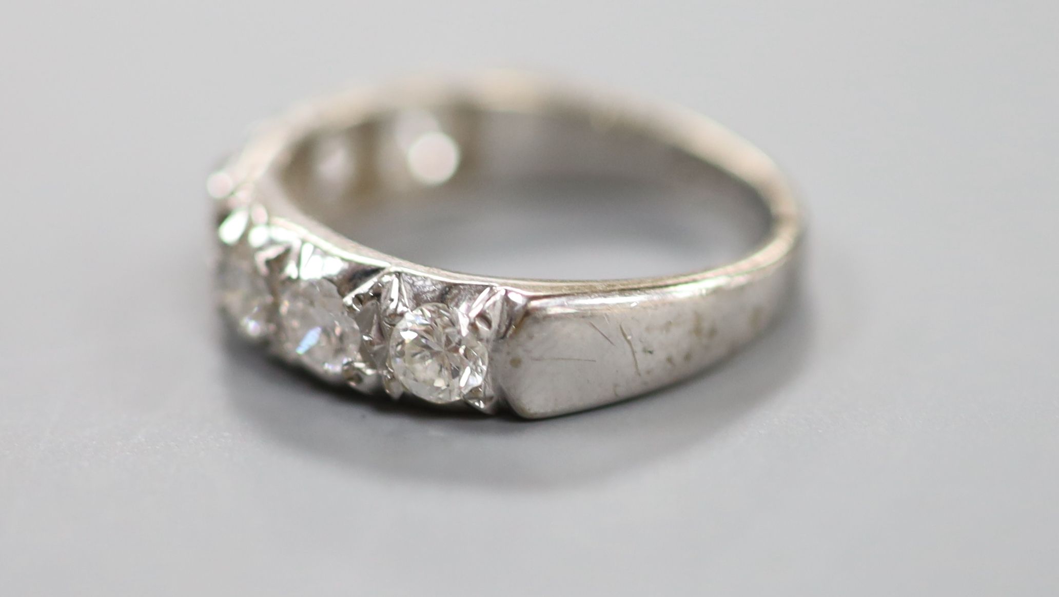 A modern 18ct white gold and seven stone diamond set half hoop ring
